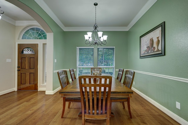 dining area with ornamental molding, light wood-type flooring, and a chandelier