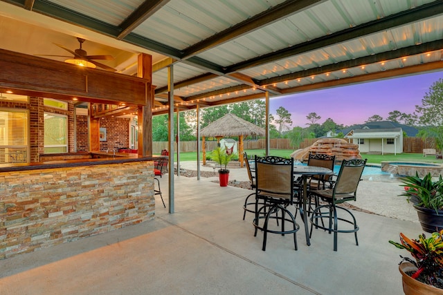 patio terrace at dusk with a gazebo, ceiling fan, and a fenced in pool