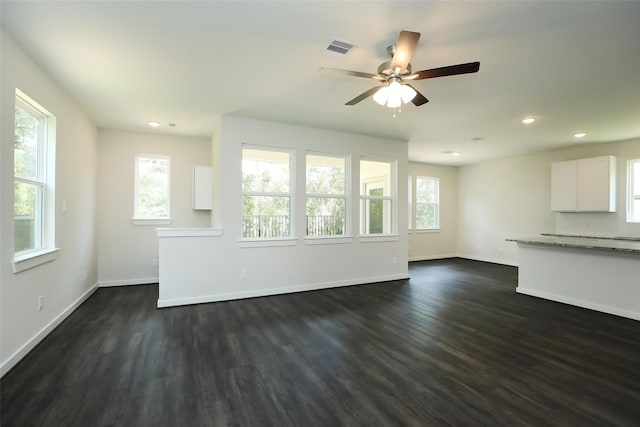 unfurnished living room with ceiling fan, a wealth of natural light, and dark hardwood / wood-style flooring