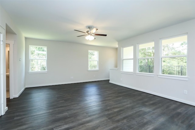 spare room featuring a healthy amount of sunlight, ceiling fan, and dark wood-type flooring