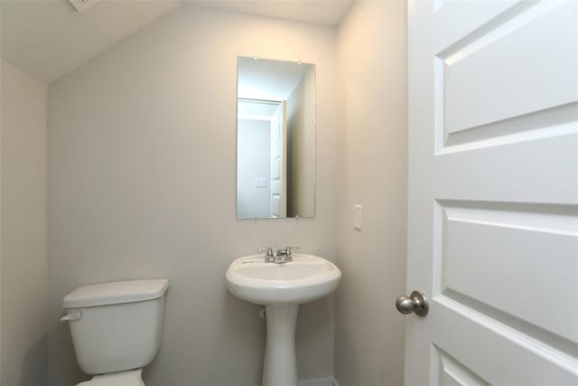 bathroom with sink, lofted ceiling, and toilet