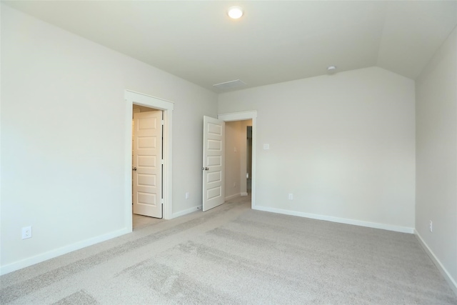 carpeted spare room featuring vaulted ceiling