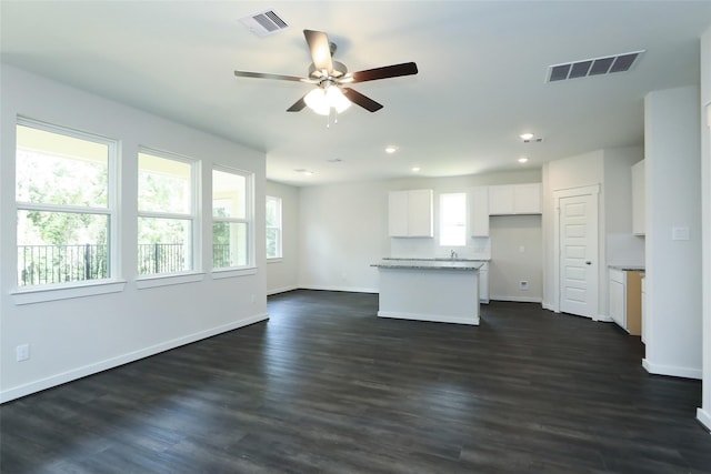 kitchen featuring ceiling fan, a kitchen island, light stone counters, dark hardwood / wood-style floors, and white cabinets