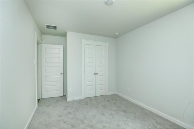 unfurnished bedroom with a closet and light colored carpet