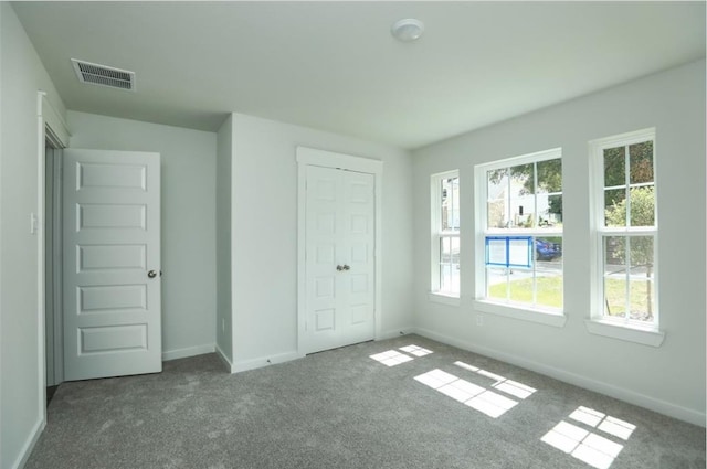 unfurnished bedroom with a closet, carpet, and multiple windows