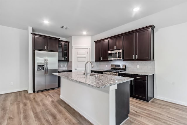 12135 Mustang Ave, Willis, TX 77378 - kitchen featuring appliances with stainless steel finishes, light wood-style flooring, dark brown cabinetry, and recessed lighting