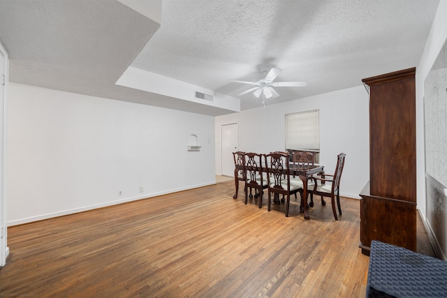 dining space with ceiling fan, a textured ceiling, and hardwood / wood-style floors