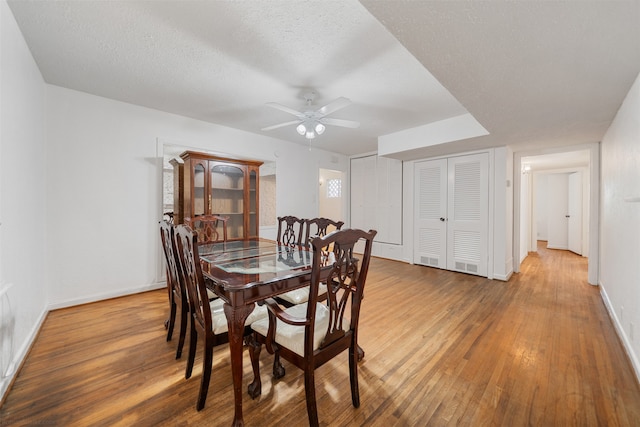 dining space featuring ceiling fan, wood-type flooring, and a textured ceiling