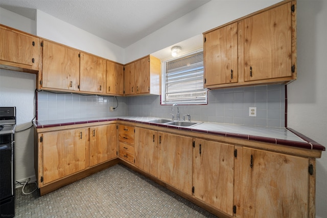 kitchen featuring decorative backsplash, sink, and tile countertops