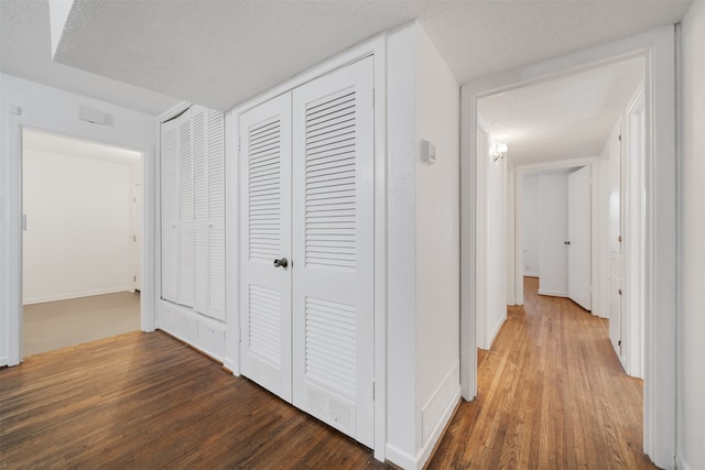 corridor featuring dark hardwood / wood-style flooring and a textured ceiling