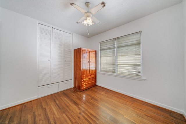 unfurnished bedroom with a closet, hardwood / wood-style flooring, and ceiling fan