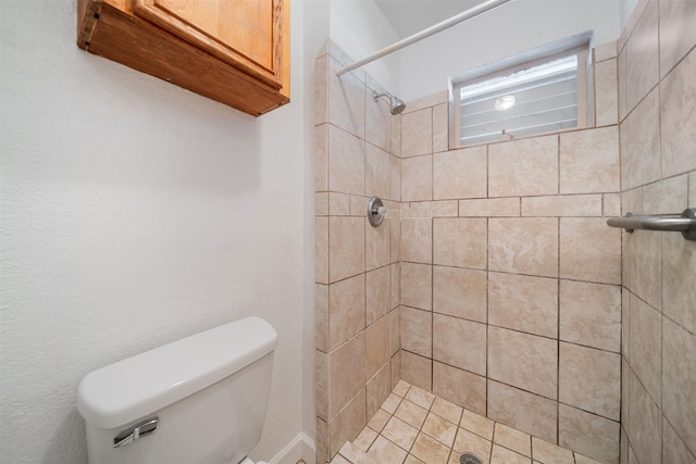 bathroom featuring tiled shower and toilet