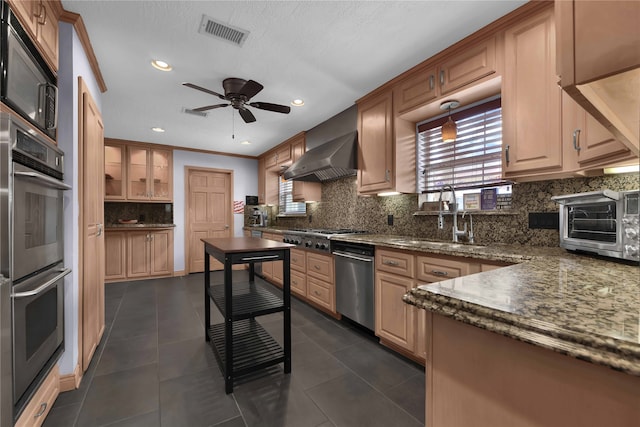 kitchen featuring stainless steel appliances, wall chimney range hood, dark tile patterned floors, and ornamental molding