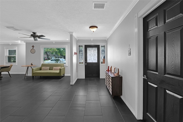 foyer featuring ceiling fan, a textured ceiling, dark tile patterned flooring, and ornamental molding