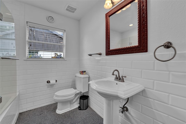 bathroom featuring tile patterned flooring, tile walls, and toilet