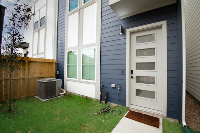 doorway to property with cooling unit and a lawn