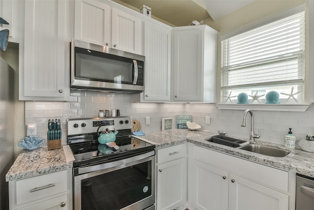 kitchen with stainless steel appliances, white cabinets, and decorative backsplash