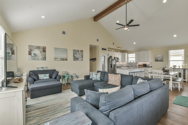 living room with high vaulted ceiling, beam ceiling, light wood-type flooring, and ceiling fan