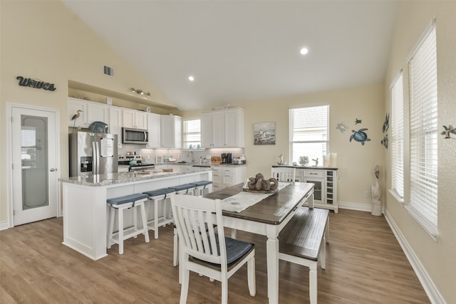 dining space with light hardwood / wood-style floors, high vaulted ceiling, and sink