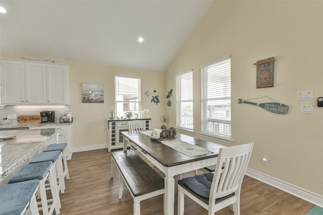 dining area featuring light hardwood / wood-style flooring and high vaulted ceiling