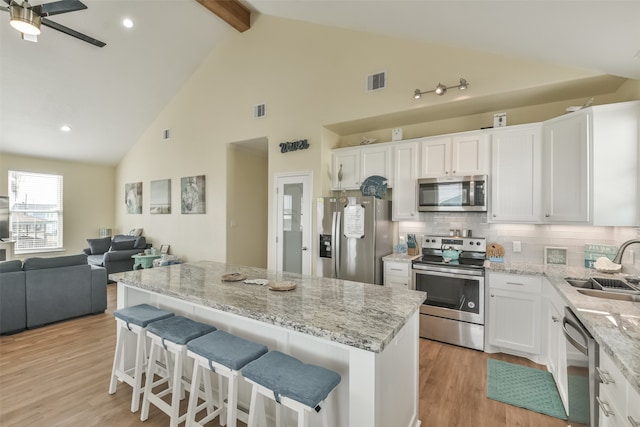 kitchen featuring tasteful backsplash, white cabinets, sink, light hardwood / wood-style flooring, and appliances with stainless steel finishes