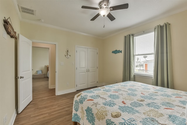 bedroom featuring hardwood / wood-style flooring, crown molding, ceiling fan, and a closet