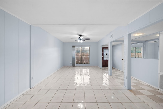 spare room with ceiling fan, crown molding, and light tile patterned floors