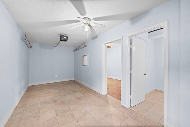 empty room with ceiling fan, light tile patterned flooring, and a textured ceiling