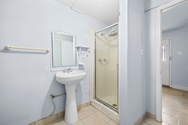 bathroom with tile patterned flooring, an enclosed shower, and sink