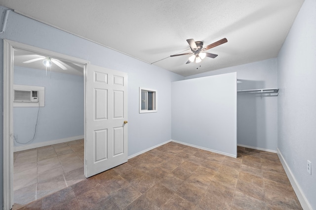 unfurnished bedroom featuring ceiling fan, a textured ceiling, a wall mounted AC, and a closet