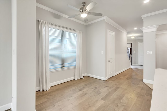 empty room with ornate columns, ceiling fan, ornamental molding, and light wood-type flooring