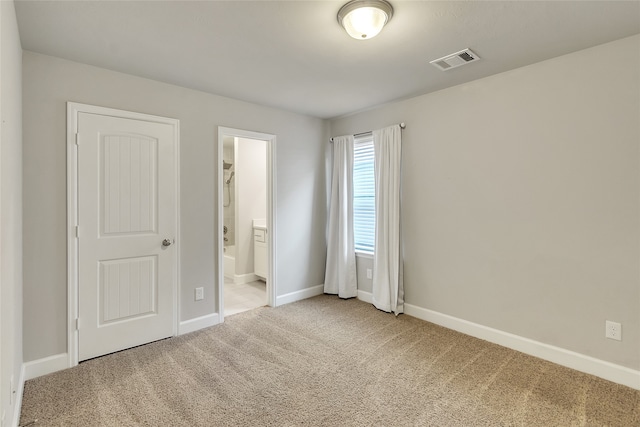 unfurnished bedroom with a closet, ensuite bath, and carpet flooring