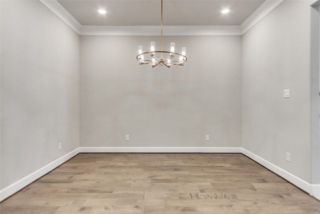 unfurnished dining area featuring crown molding, a chandelier, and light wood-type flooring