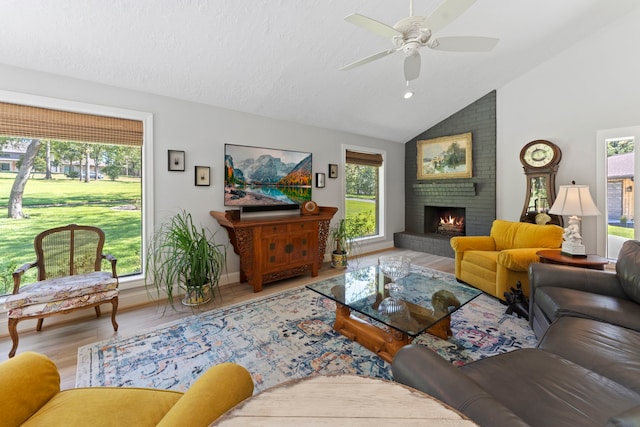 living room featuring ceiling fan, a fireplace, hardwood / wood-style floors, and a healthy amount of sunlight