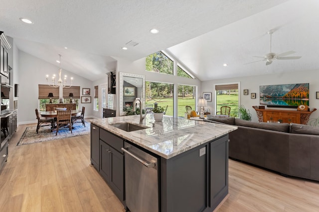 kitchen featuring light stone countertops, sink, appliances with stainless steel finishes, light hardwood / wood-style flooring, and a center island with sink