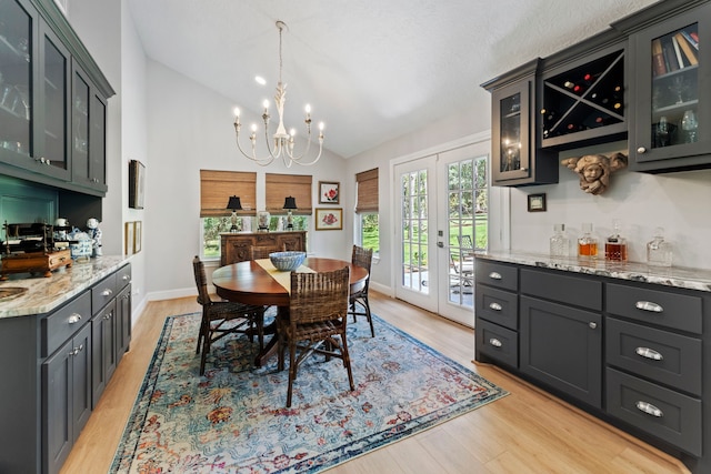 dining space featuring french doors, vaulted ceiling, an inviting chandelier, and light hardwood / wood-style flooring