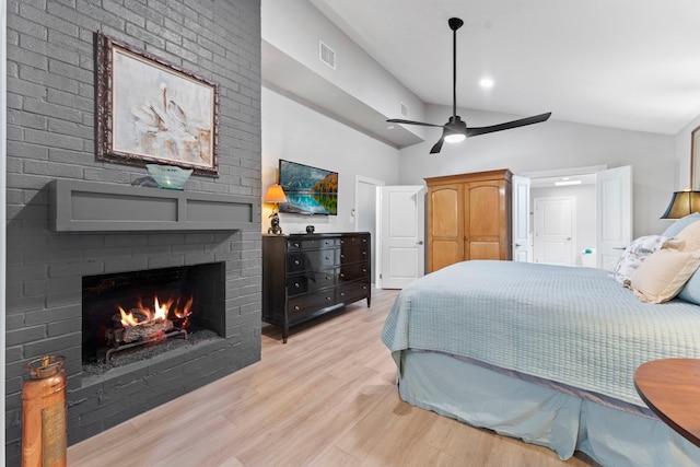 bedroom with lofted ceiling, ceiling fan, a brick fireplace, and light hardwood / wood-style flooring