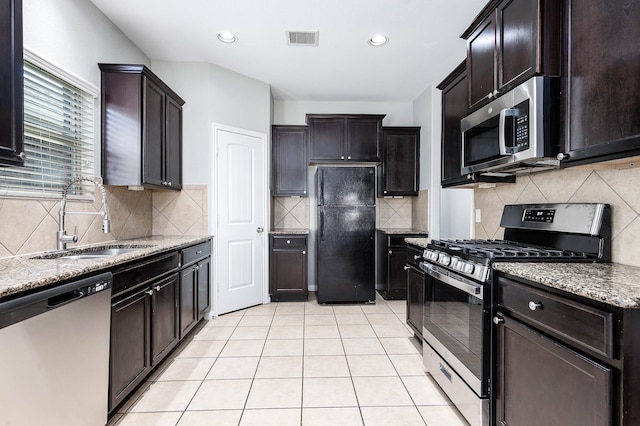 kitchen featuring tasteful backsplash, dark brown cabinets, sink, appliances with stainless steel finishes, and light tile patterned floors