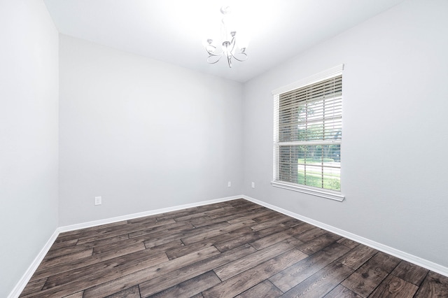 unfurnished room featuring an inviting chandelier and dark wood-type flooring