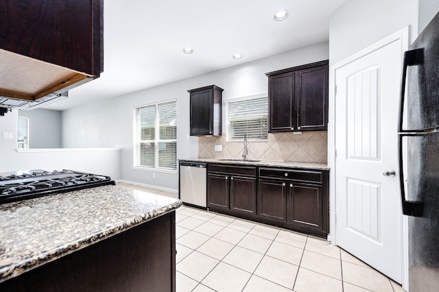 kitchen with light tile patterned flooring, light stone countertops, sink, and stainless steel dishwasher