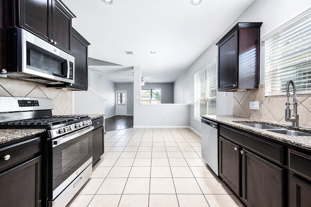 kitchen featuring ceiling fan, light stone counters, sink, backsplash, and stainless steel appliances