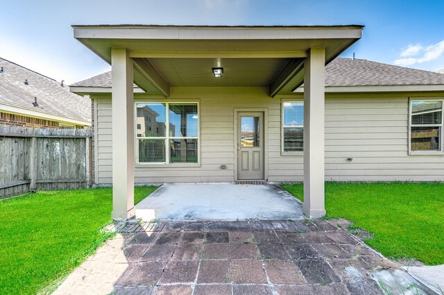12915 Madison Boulder Ln, Humble, TX 77346 - view of exterior entry with a lawn, a patio, fence, and roof with shingles