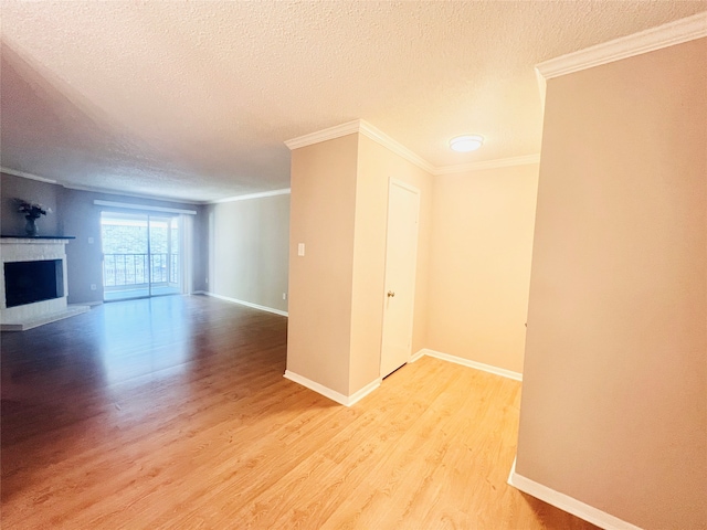 unfurnished living room with a textured ceiling, crown molding, a tiled fireplace, and wood-type flooring