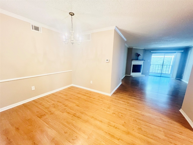 unfurnished living room featuring ornamental molding, a chandelier, hardwood / wood-style flooring, and a textured ceiling