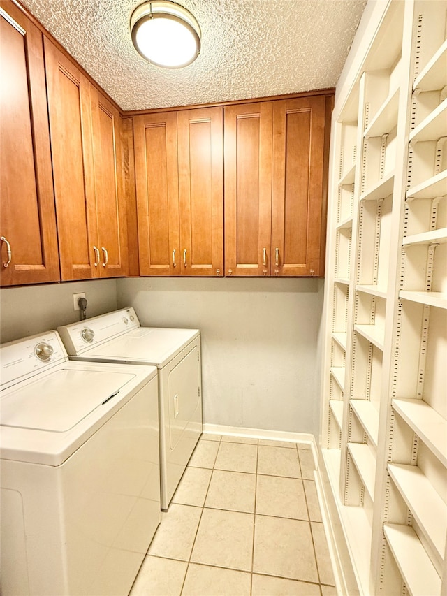 washroom with cabinets, a textured ceiling, washing machine and dryer, and light tile patterned floors