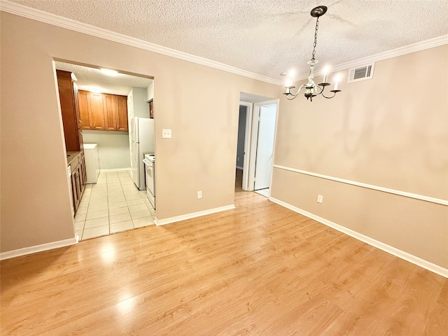 unfurnished dining area with independent washer and dryer, a textured ceiling, and light wood-type flooring