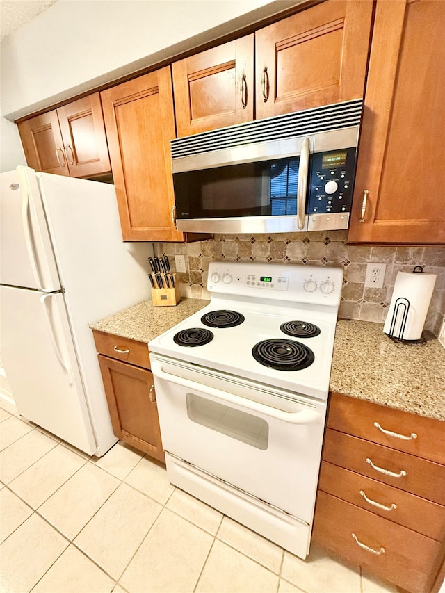 kitchen with light stone counters, white appliances, and light tile patterned floors