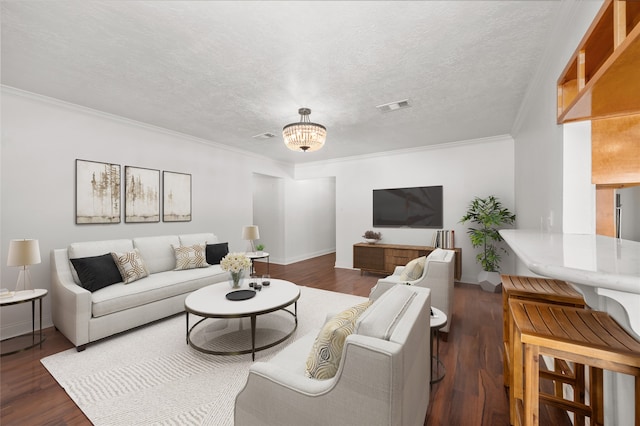 living room featuring dark hardwood / wood-style floors, crown molding, an inviting chandelier, and a textured ceiling