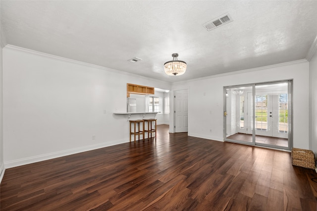 unfurnished living room with a notable chandelier, crown molding, dark hardwood / wood-style floors, and a textured ceiling