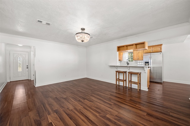 unfurnished living room featuring crown molding, sink, dark hardwood / wood-style floors, and a textured ceiling